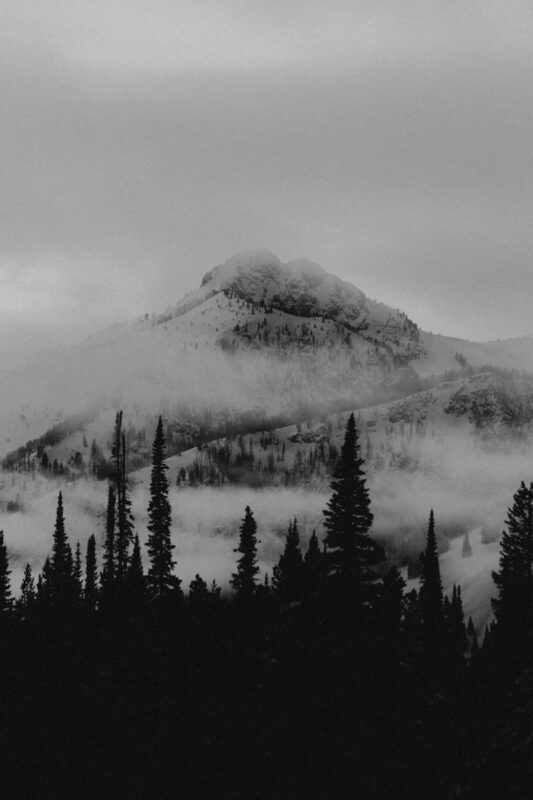 a black and white photo of a mountain covered in fog