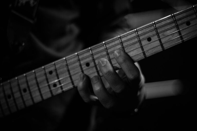 person playing guitar in grayscale photography